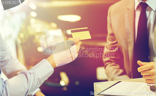 Image of customer giving credit card to car dealer in salon