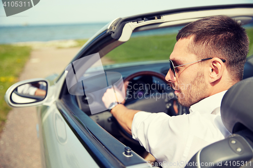 Image of happy man driving cabriolet car outdoors