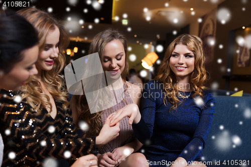 Image of woman showing engagement ring to her friends