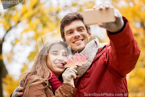 Image of couple taking selfie by smartphone in autumn park