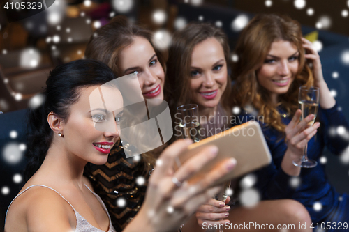 Image of women with champagne taking selfie at night club