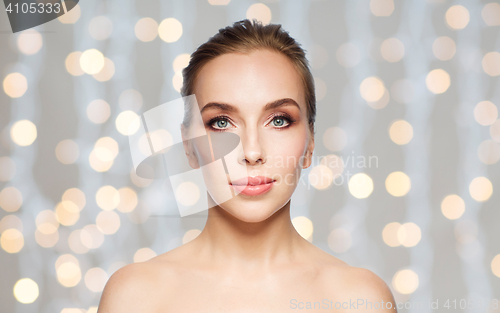 Image of beautiful young woman face over holidays lights