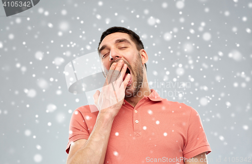 Image of tired yawning man over snow background