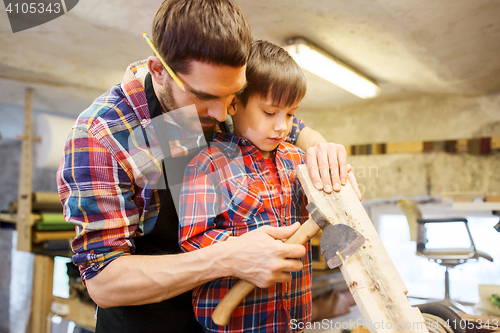 Image of father and son with ax and wood plank at workshop