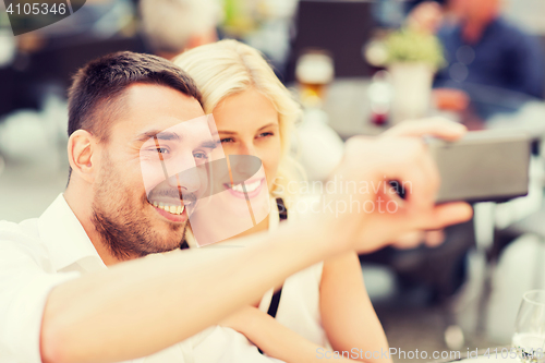 Image of happy couple taking selfie with smartphone at cafe