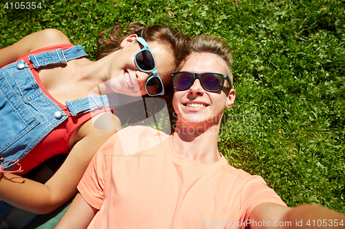 Image of happy teenage couple taking selfie on summer grass