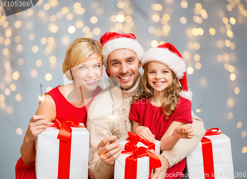 Image of happy family holding gift boxes and sparkles