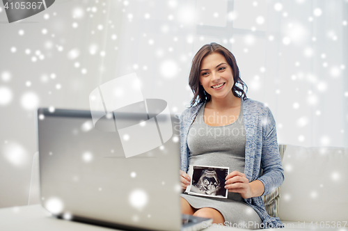 Image of happy pregnant woman with ultrasound image at home