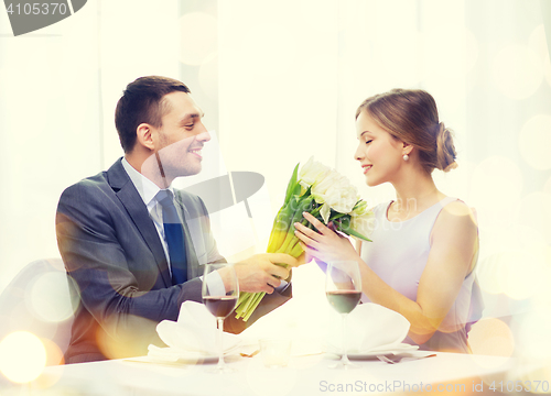 Image of smiling man giving flower bouquet at restaurant