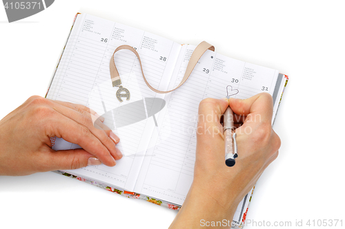 Image of Notebook opened with female hands writing