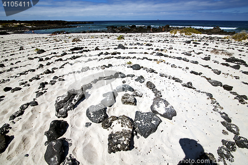 Image of spiral of black rocks in the white  beach   lanzarote spain