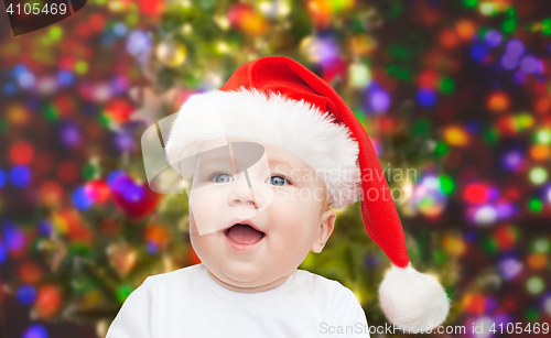 Image of baby boy in christmas santa hat over blue lights