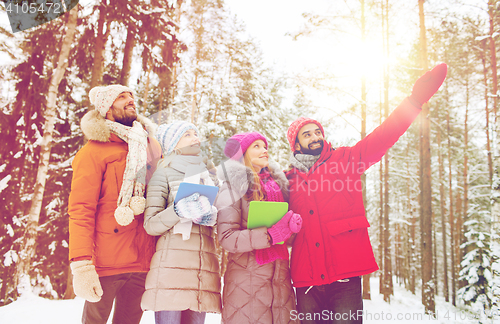 Image of smiling friends with tablet pc in winter forest