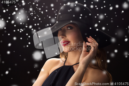 Image of beautiful woman in black hat over snow