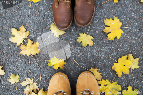 Image of couple of feet in boots and autumn leaves