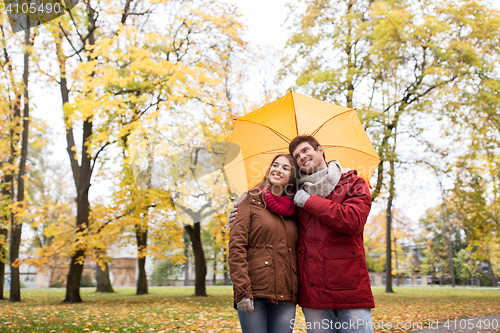 Image of smiling couple with umbrella in autumn park