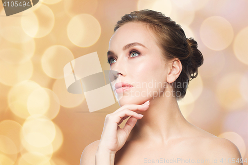 Image of beautiful woman touching her face over lights