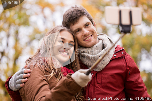 Image of couple taking selfie by smartphone in autumn park