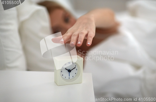 Image of close up of woman with alarm clock in bed at home