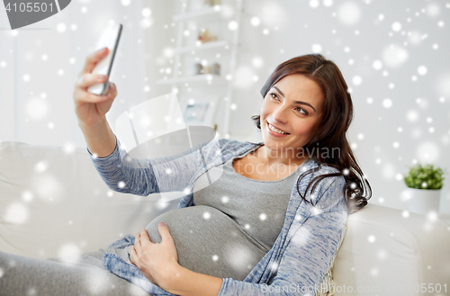 Image of pregnant woman taking smartphone selfie at home