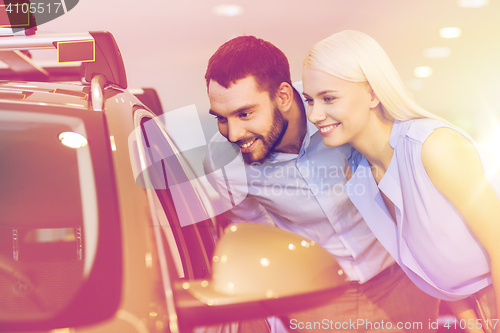 Image of happy couple buying car in auto show or salon