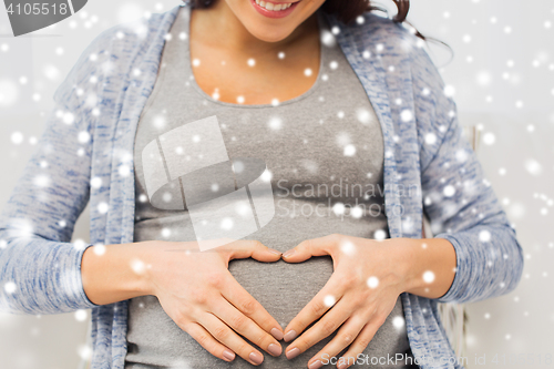 Image of close up of happy pregnant woman making heart