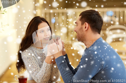 Image of happy couple with tea holding hands at restaurant