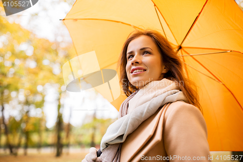 Image of happy woman with umbrella walking in autumn park