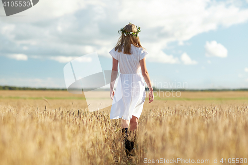 Image of happy young woman in flower wreath on cereal field