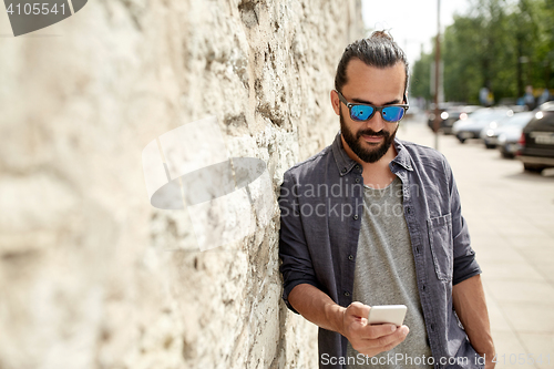 Image of man texting message on smartphone at stone wall