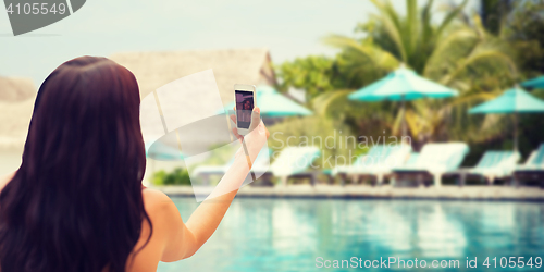 Image of young woman taking selfie with smartphone