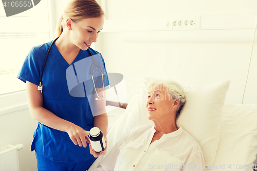 Image of nurse giving medicine to senior woman at hospital