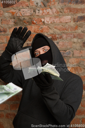 Image of Robber in mask throws banknotes