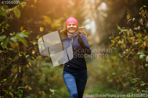 Image of Happy woman athlete Jogging in autumn forest. Healthy lifestyle concept