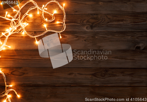 Image of Christmas dark brown wooden background decorated with shining lights