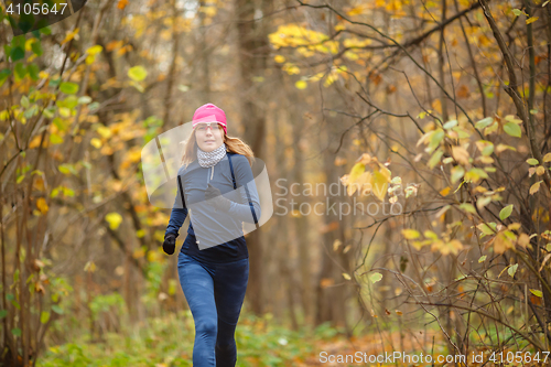 Image of Young athletic woman running in autumn colorful forest