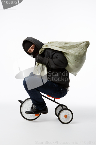 Image of Thief in mask riding bicycle