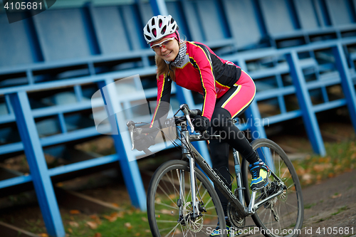 Image of Outdoors portrait of woman cyclist sitting on sports bicycle