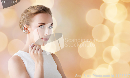 Image of woman in white with jewelry over holidays lights