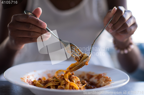 Image of a young African American woman eating pasta