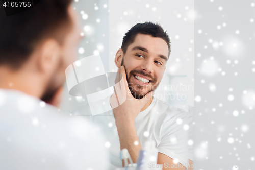 Image of happy young man looking to mirror at home bathroom