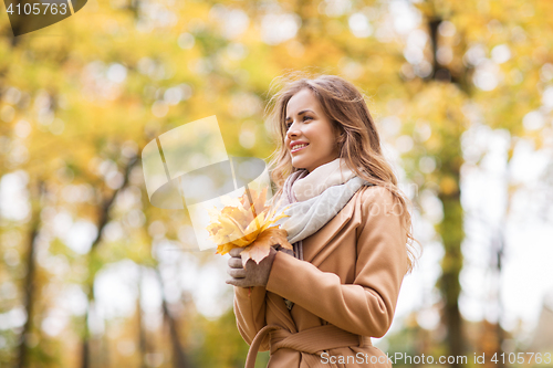 Image of beautiful woman with maple leaves in autumn park