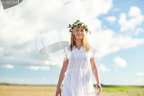 Image of smiling young woman in wreath of flowers outdoors