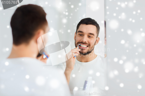 Image of man with toothbrush cleaning teeth at bathroom