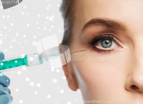 Image of close up of woman face and syringe over snow