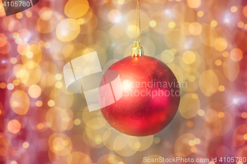 Image of close up of red christmas ball over golden lights