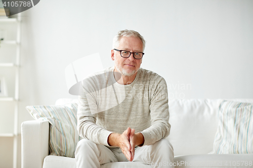 Image of smiling senior man in glasses sitting on sofa