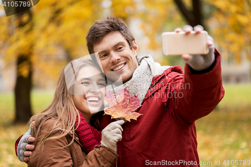 Image of couple taking selfie by smartphone in autumn park