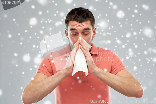 Image of sick man with paper wipe blowing nose over snow