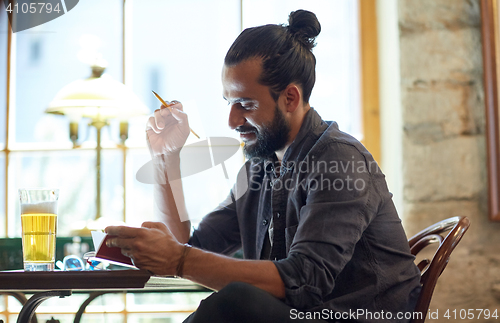 Image of close up of man with beer and notebook at pub